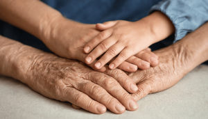 A close-up of a child's hand resting on an elderly person's hand, symbolizing comfort and connection across generations.